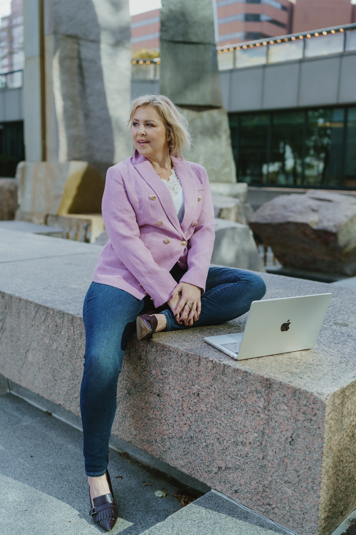 A brand strategist in a pink blazer learning SEO basics for images on her laptop outdoors.