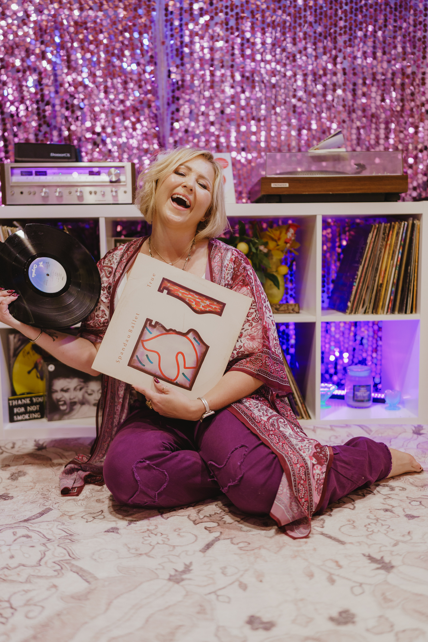 Sey laughing while holding a vinyl record and album sleeve in The Record Lair