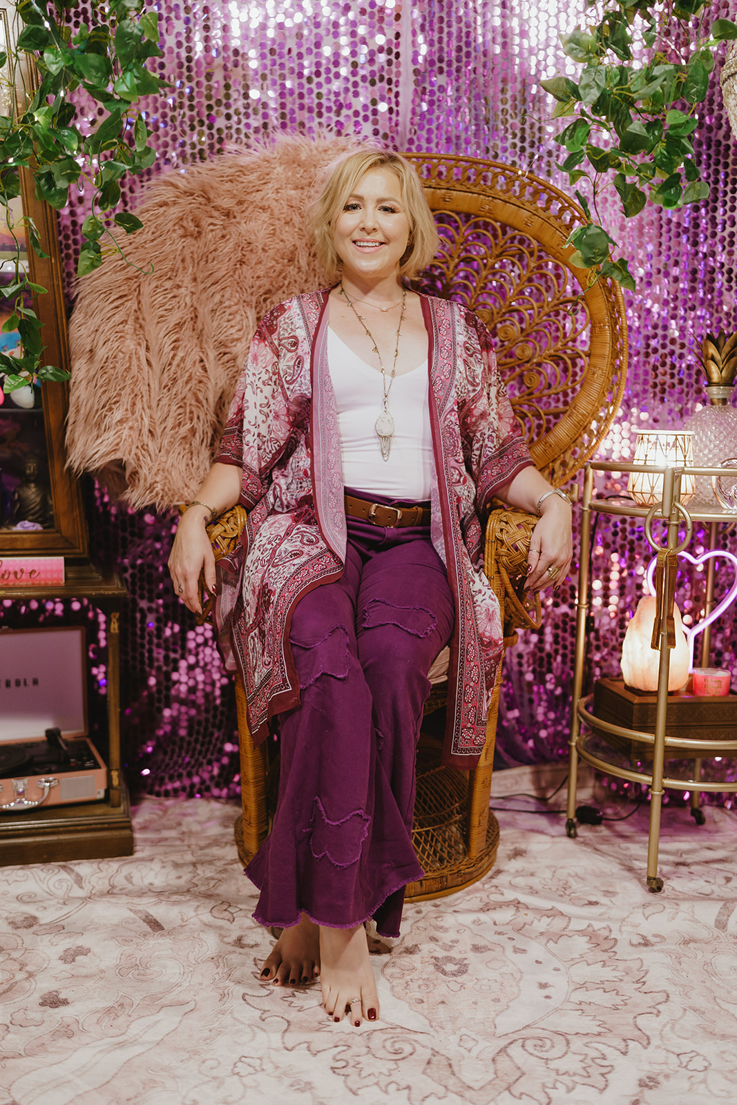 Kelsey Smith seated in a rattan peacock chair in The Record Lair