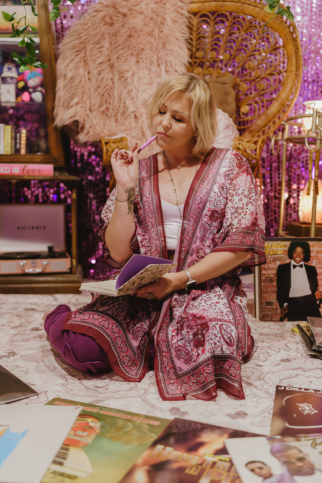 Sey reflecting with a pen and open notebook, surrounded by records in The Record Lair