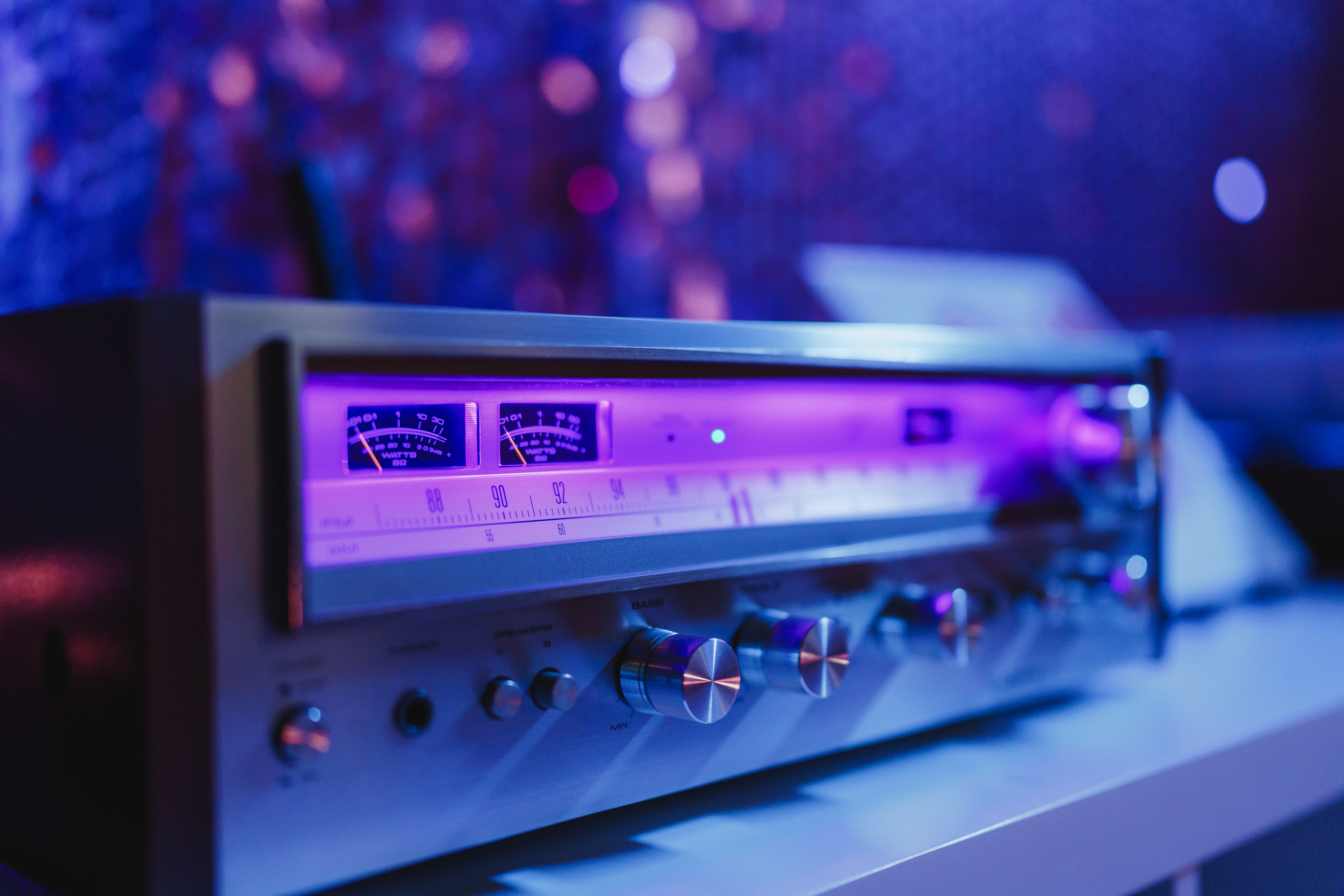 Vintage amplifier glowing in purple and blue light inside The Record Lair